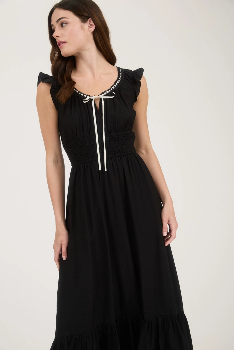 Close-up of scoop neckline with contrast ribbon tie and embroidered trim