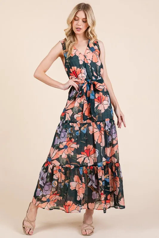 Woman wearing a floral tie waist sleeveless maxi dress with tiered skirt
