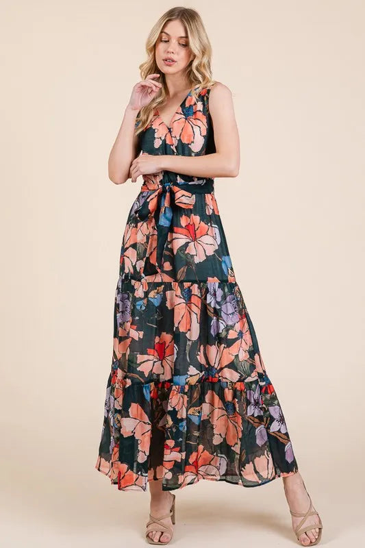 Woman wearing a floral tie waist sleeveless maxi dress with tiered skirt

